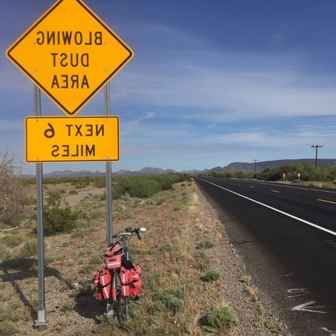 自行车和道路的路标上写着“6英里内有灰尘”